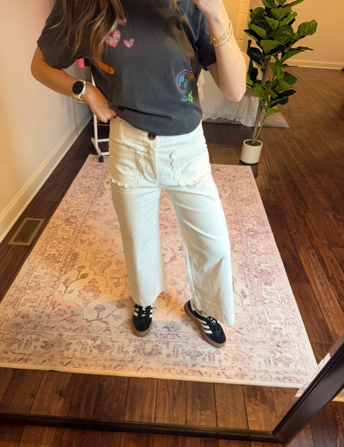 Person wearing a colorful shirt and white pants standing on a patterned rug.