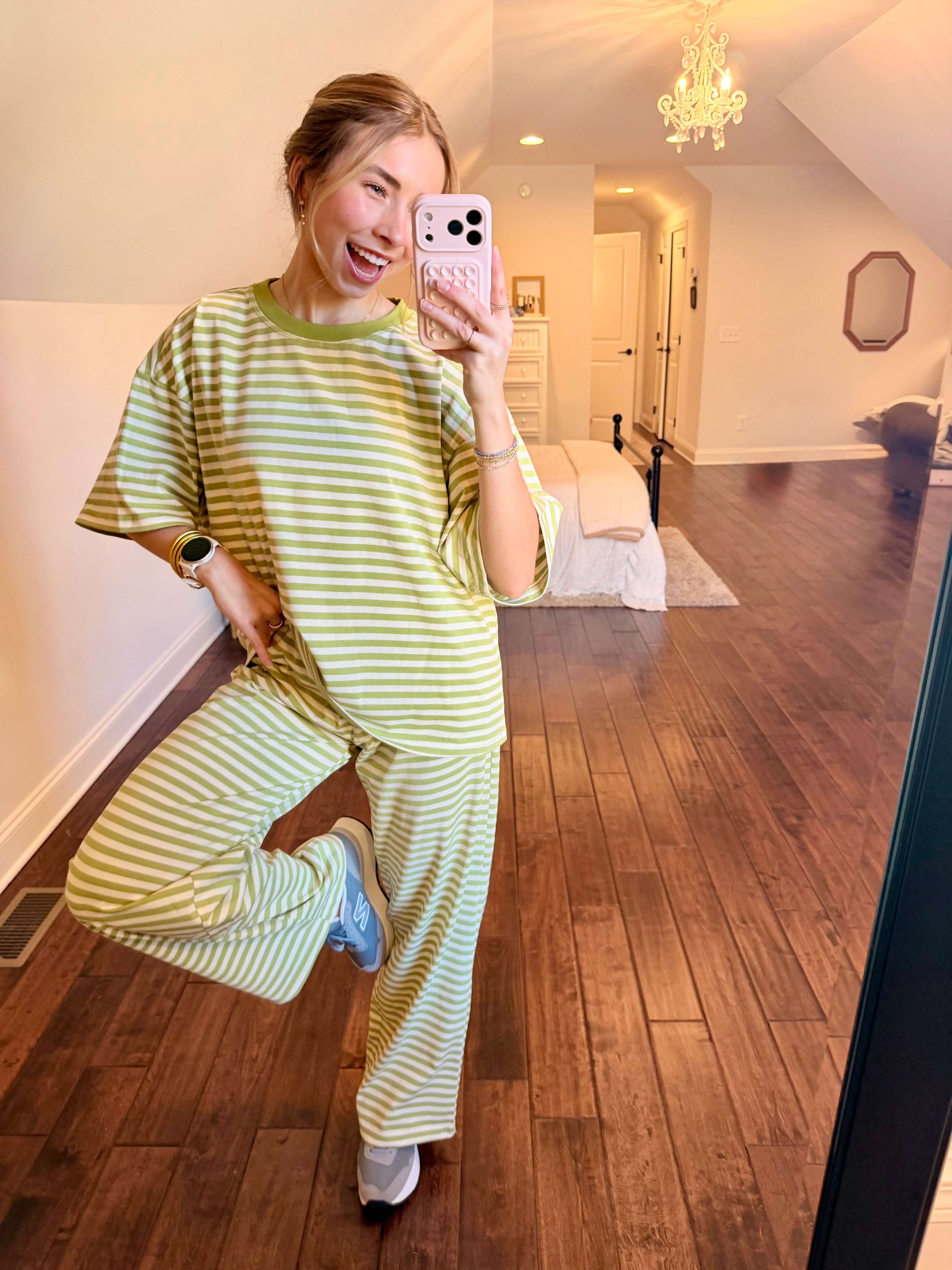 Person taking a mirror selfie wearing a green and white striped outfit in a home setting.