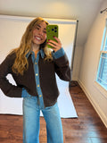 Women wearing a brown and denim sweater with jeans. 