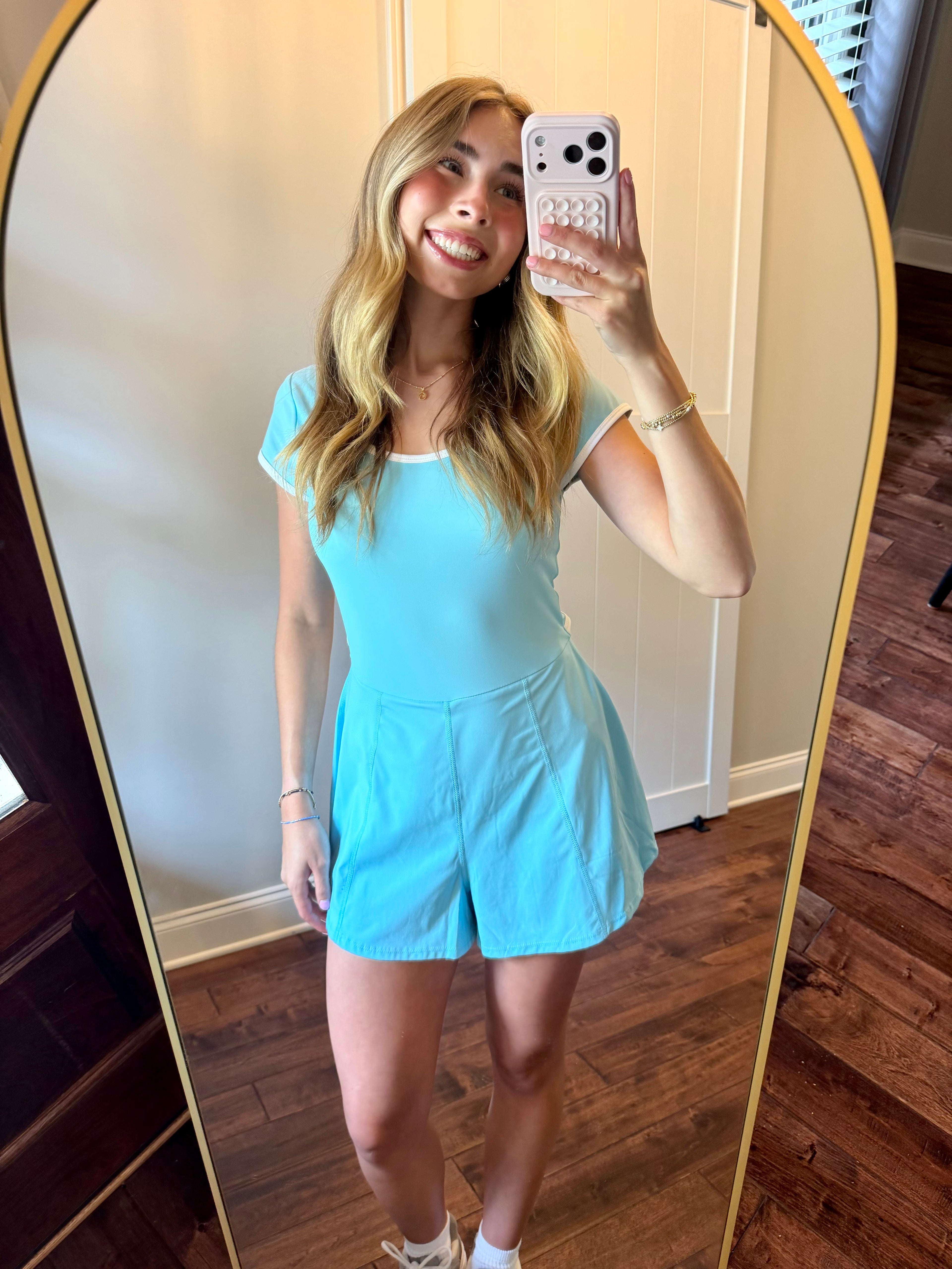 Woman taking a mirror selfie wearing a light blue romper.