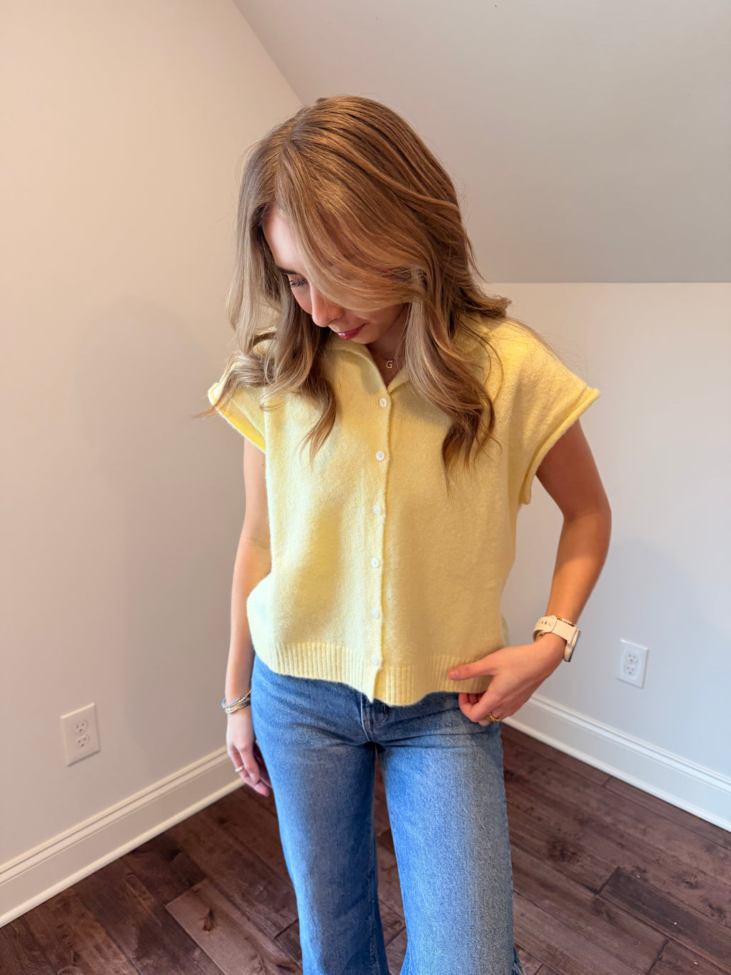 Person wearing a yellow top and blue jeans indoors.
