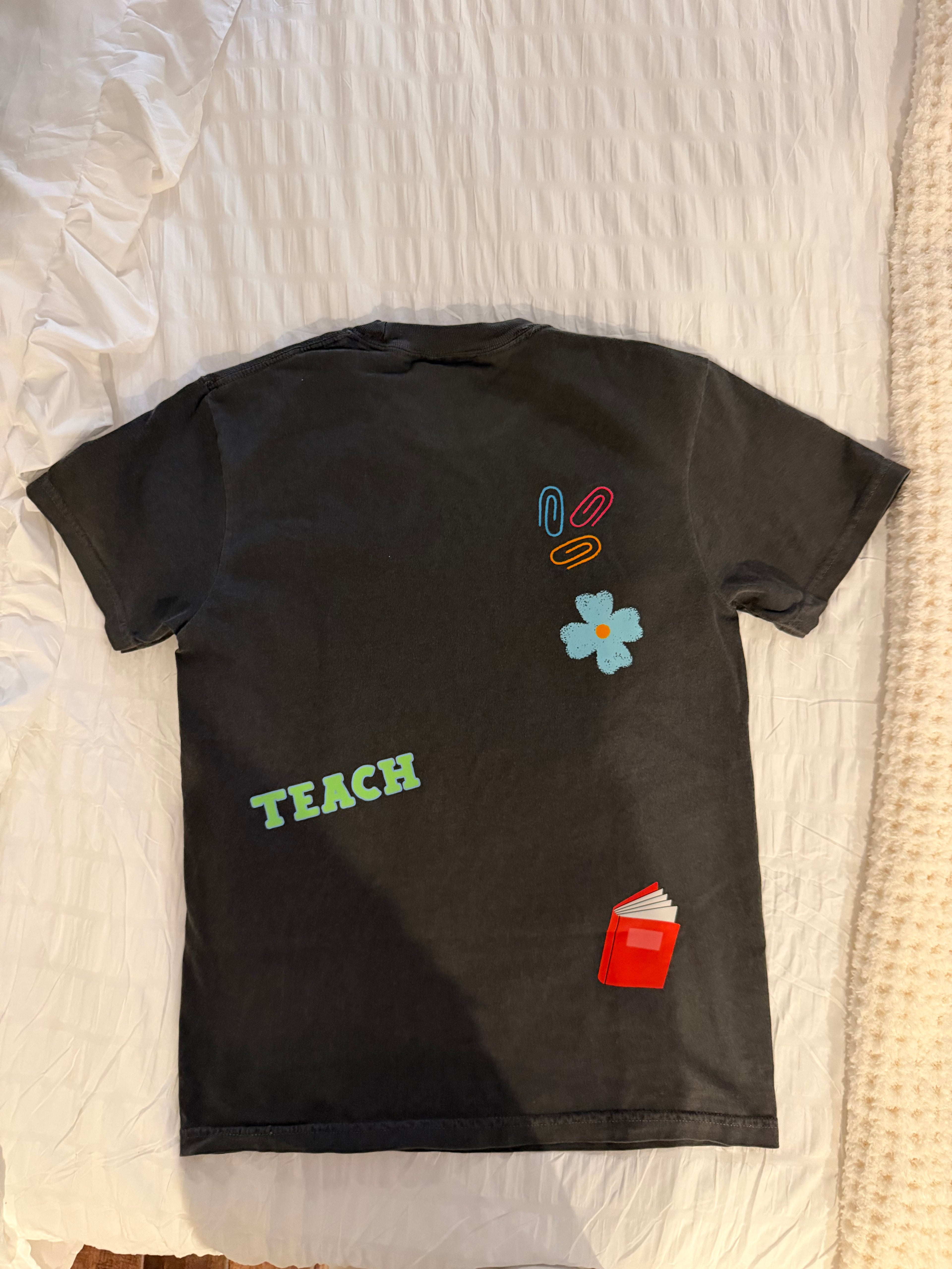 Black shirt with colorful text and graphics on a white bedspread