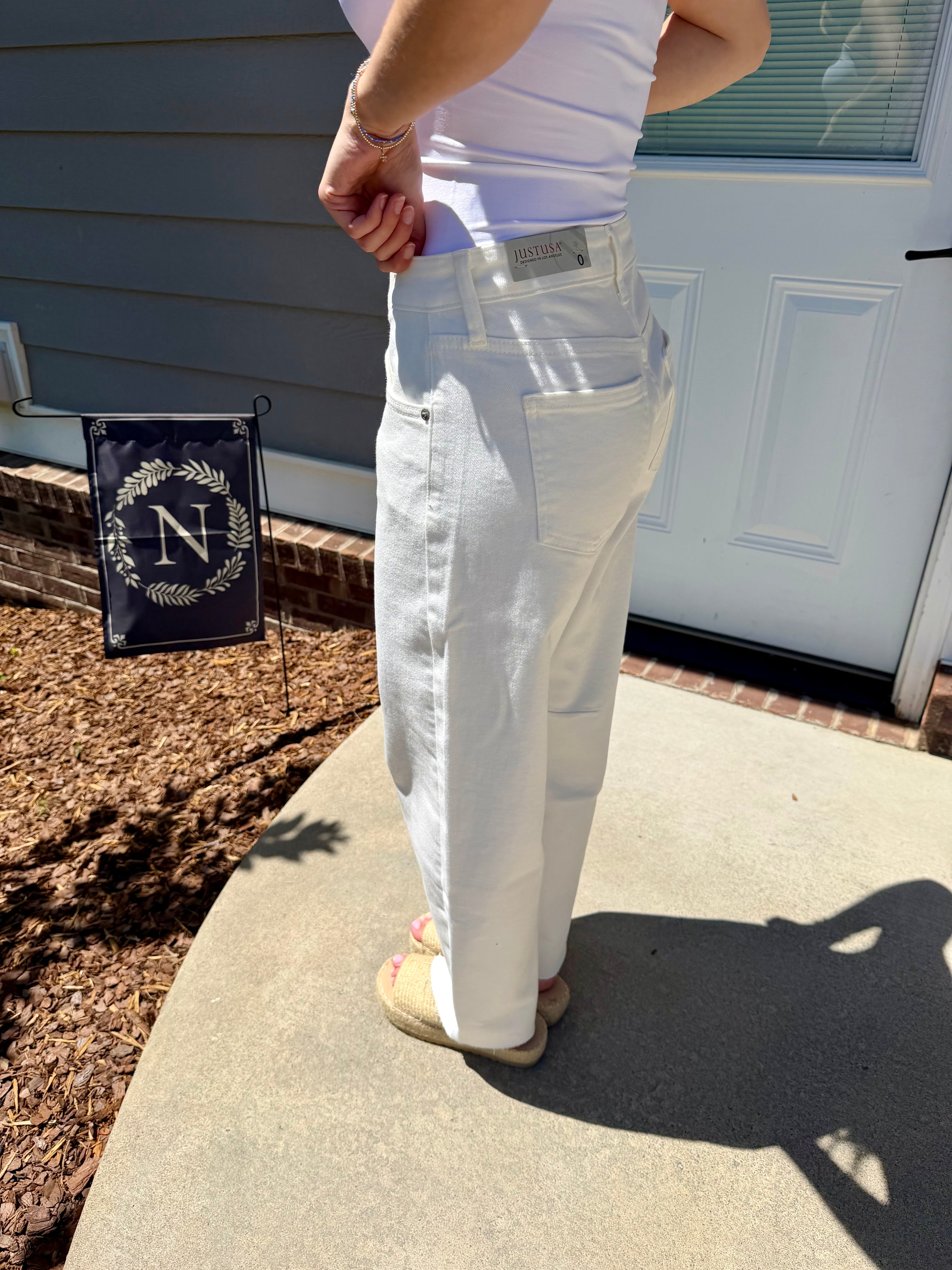 Person wearing white pants standing on a concrete step with a house in the background