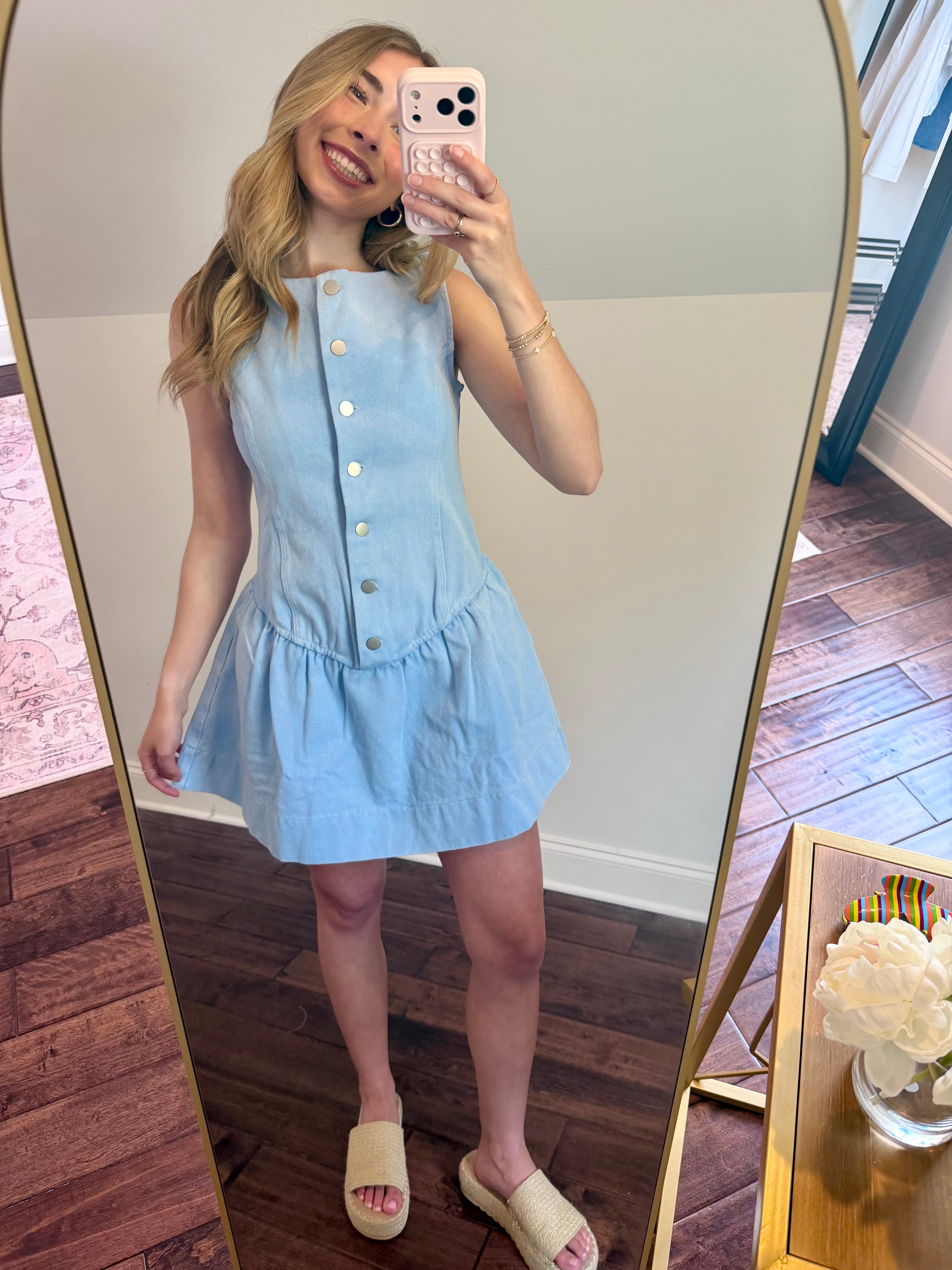 Woman taking a mirror selfie wearing a light blue dress indoors.