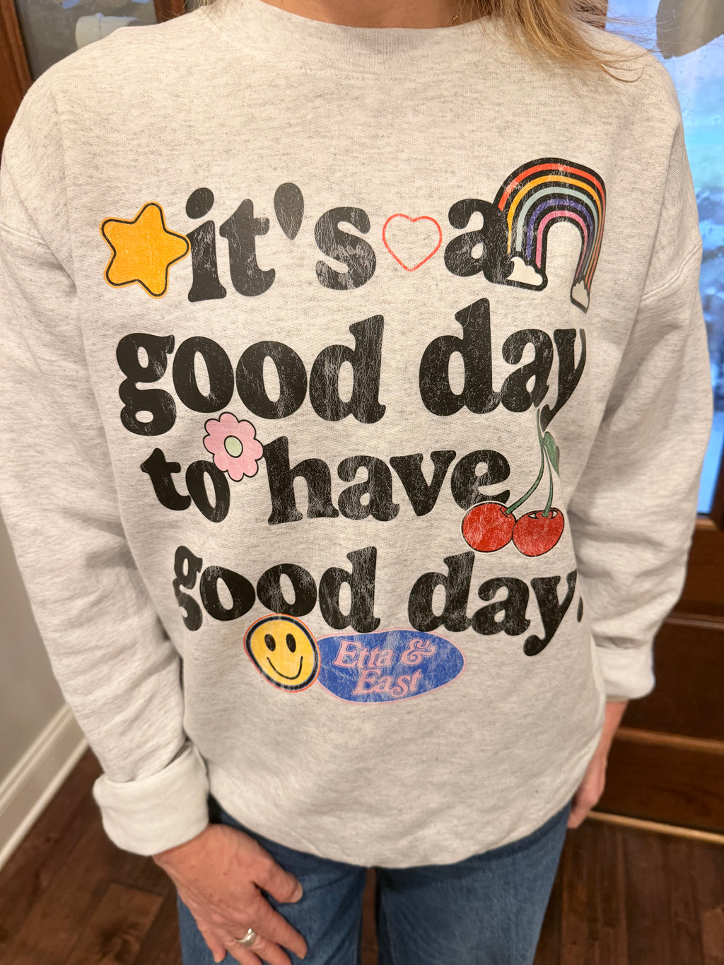 Person wearing a light gray sweatshirt with colorful text and graphics.