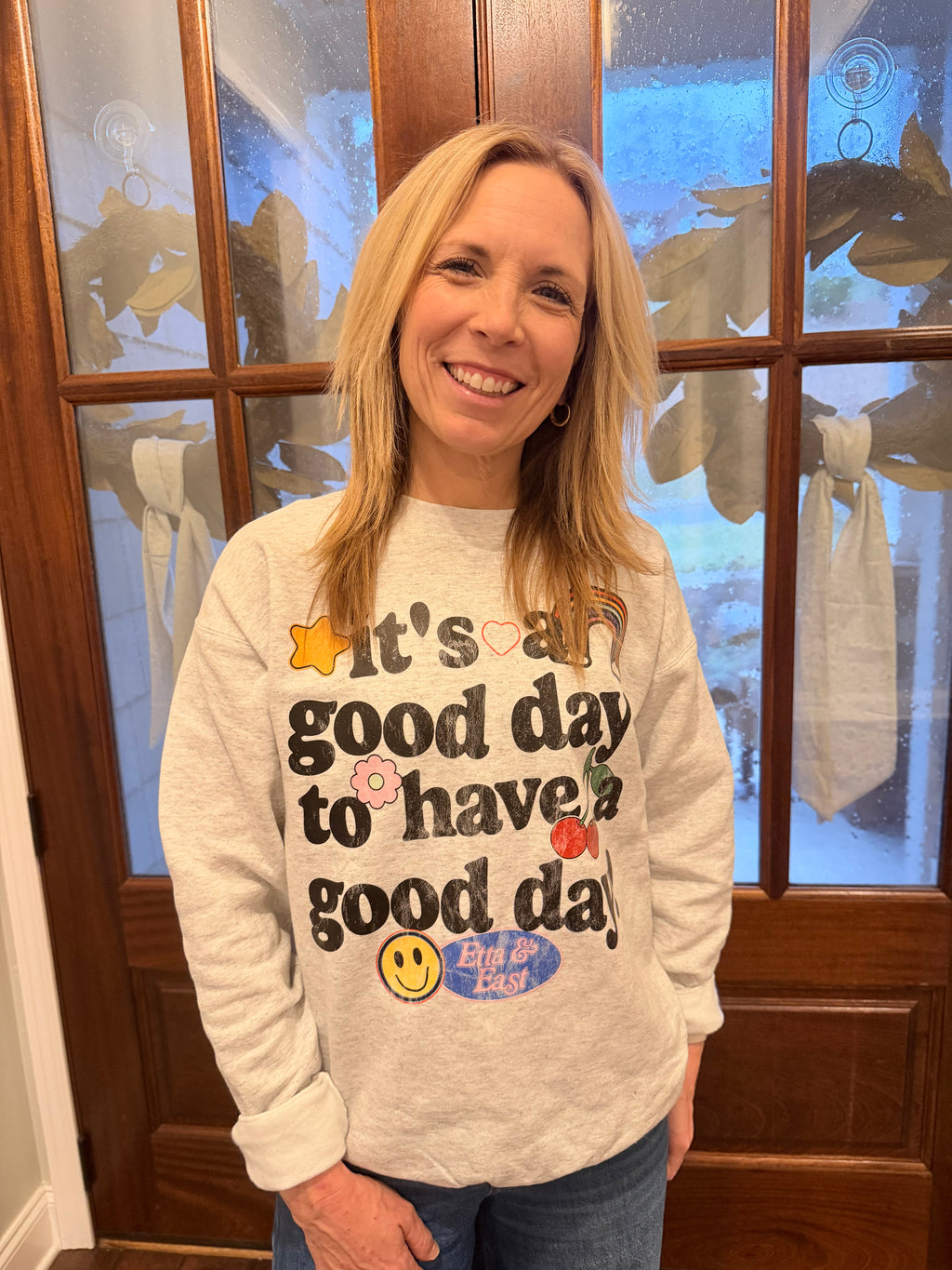 Person wearing a sweatshirt with a motivational quote in front of a wooden door.