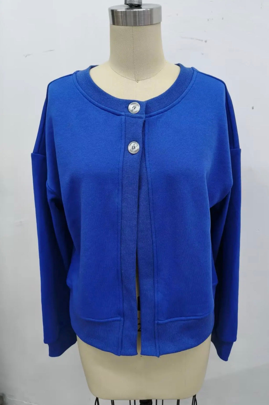 A bright royal blue long-sleeve cardigan sweater displayed on a beige dress form mannequin against a plain white wall.