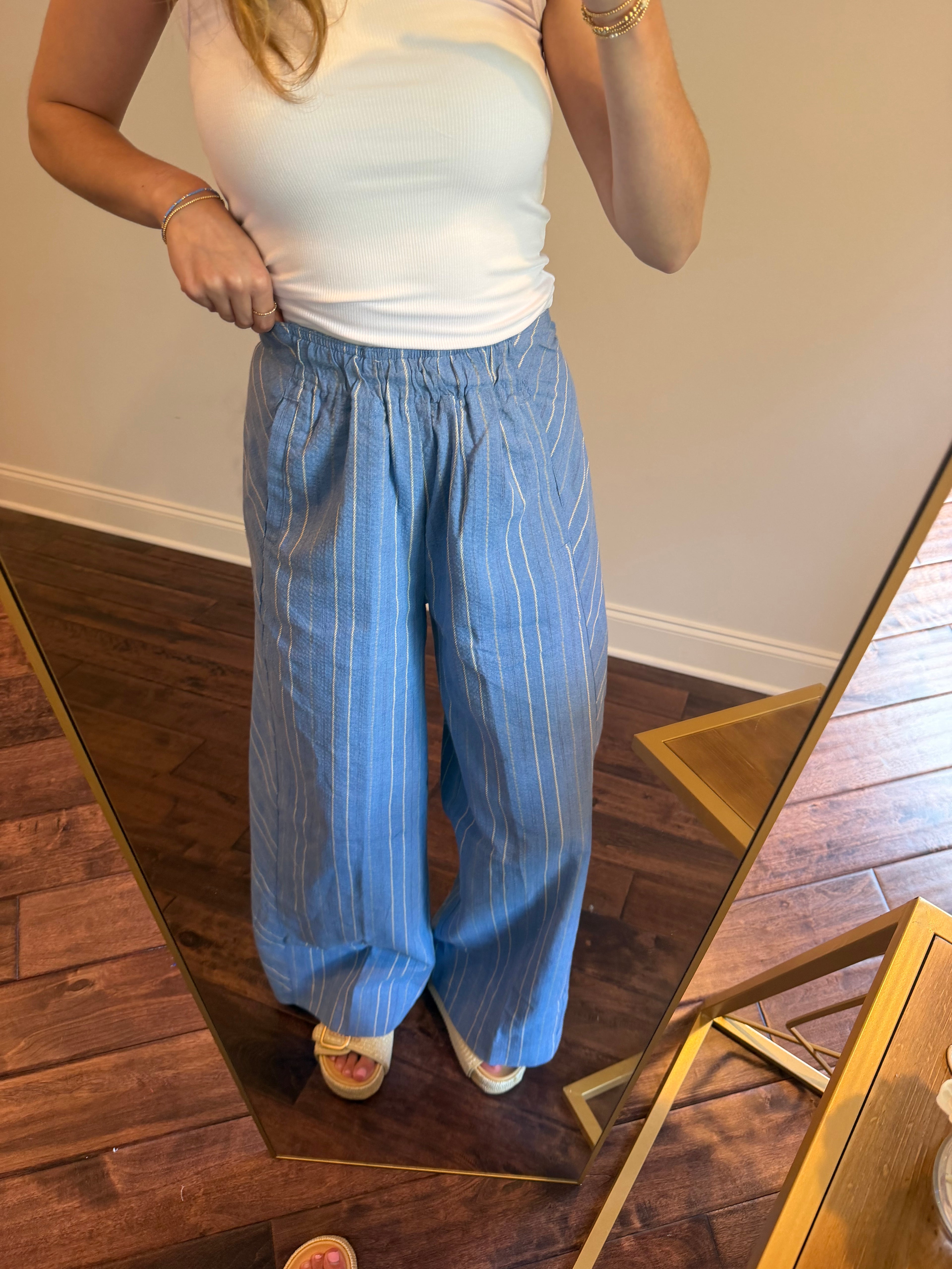 Person wearing blue pants and a white top in a room with wooden flooring.