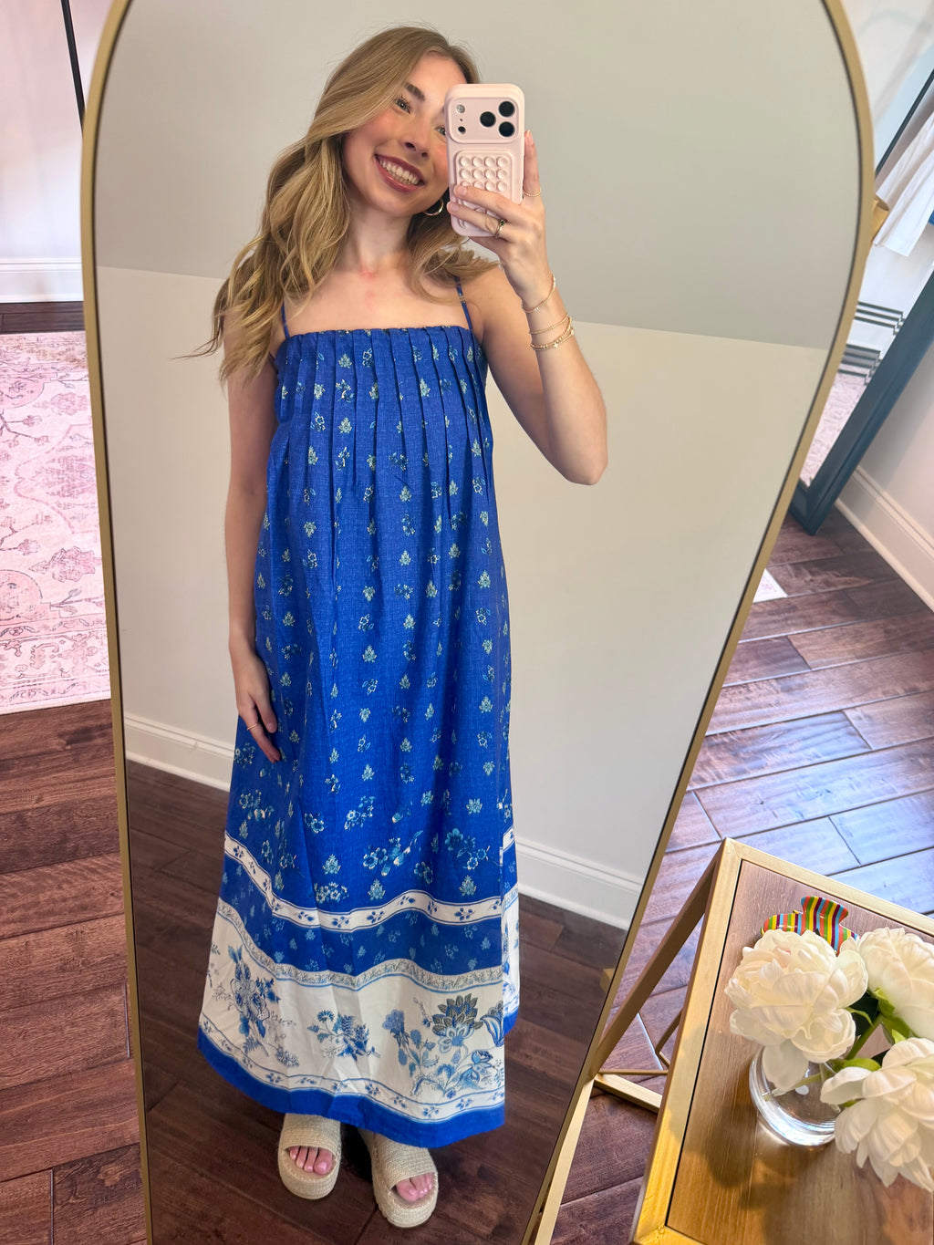 Woman taking a mirror selfie wearing a blue strapless dress with white patterns.