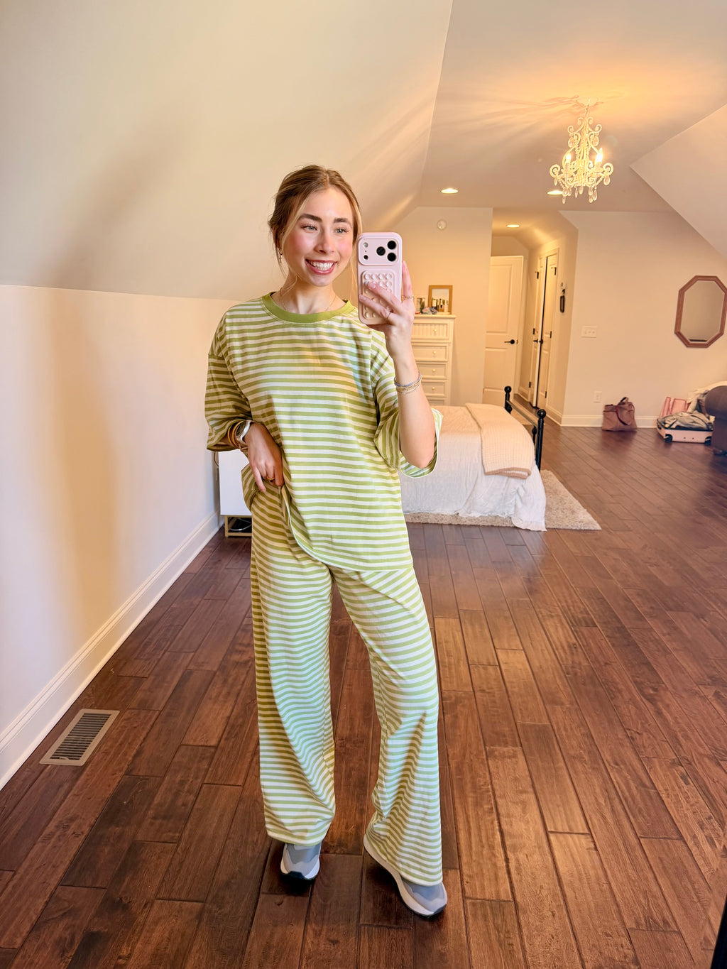 Person taking a mirror selfie wearing a striped green set in a bedroom.