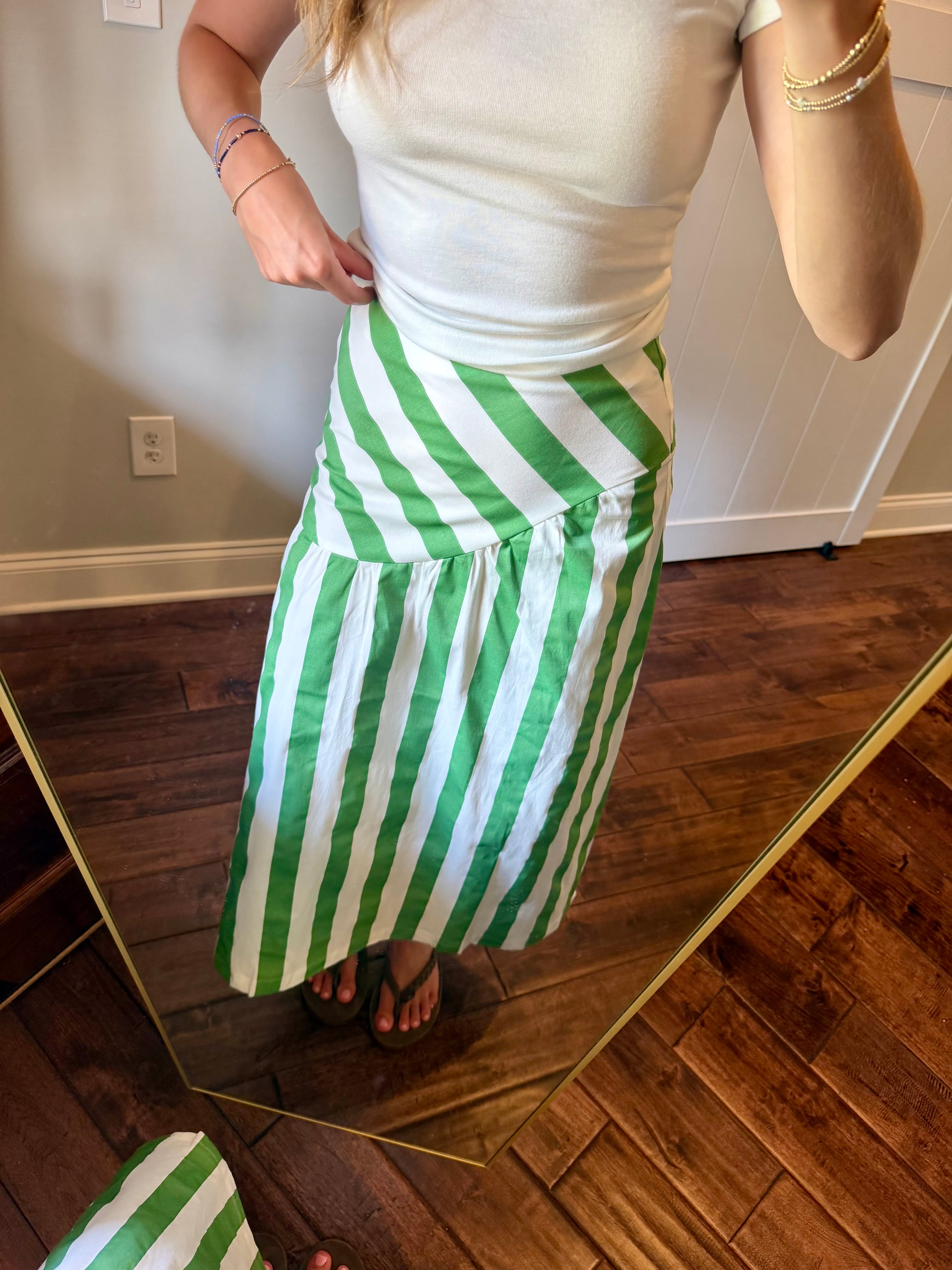 Person wearing a green and white striped skirt standing in front of a mirror.