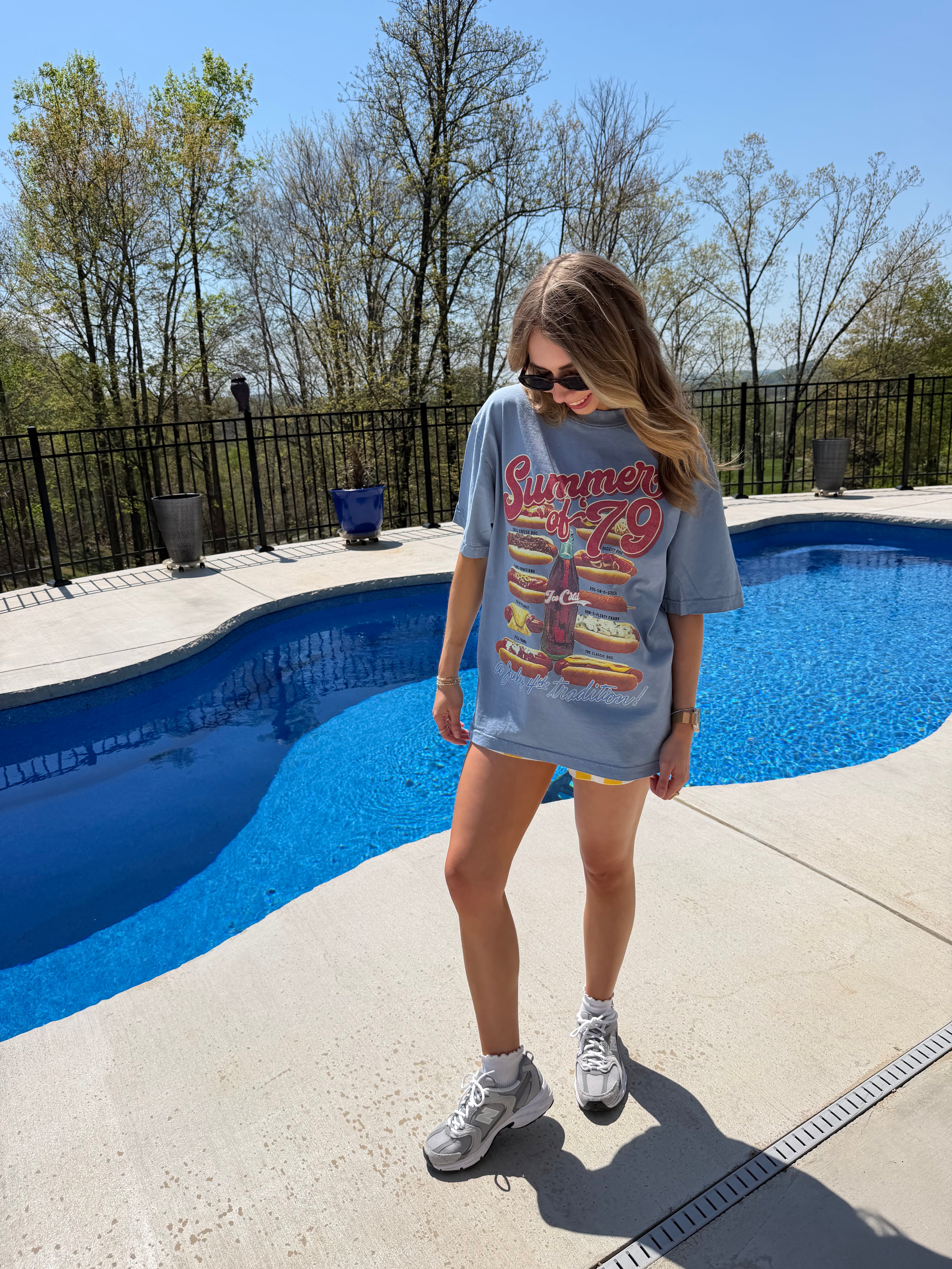 Person wearing a sweatshirt with colorful text by a poolside