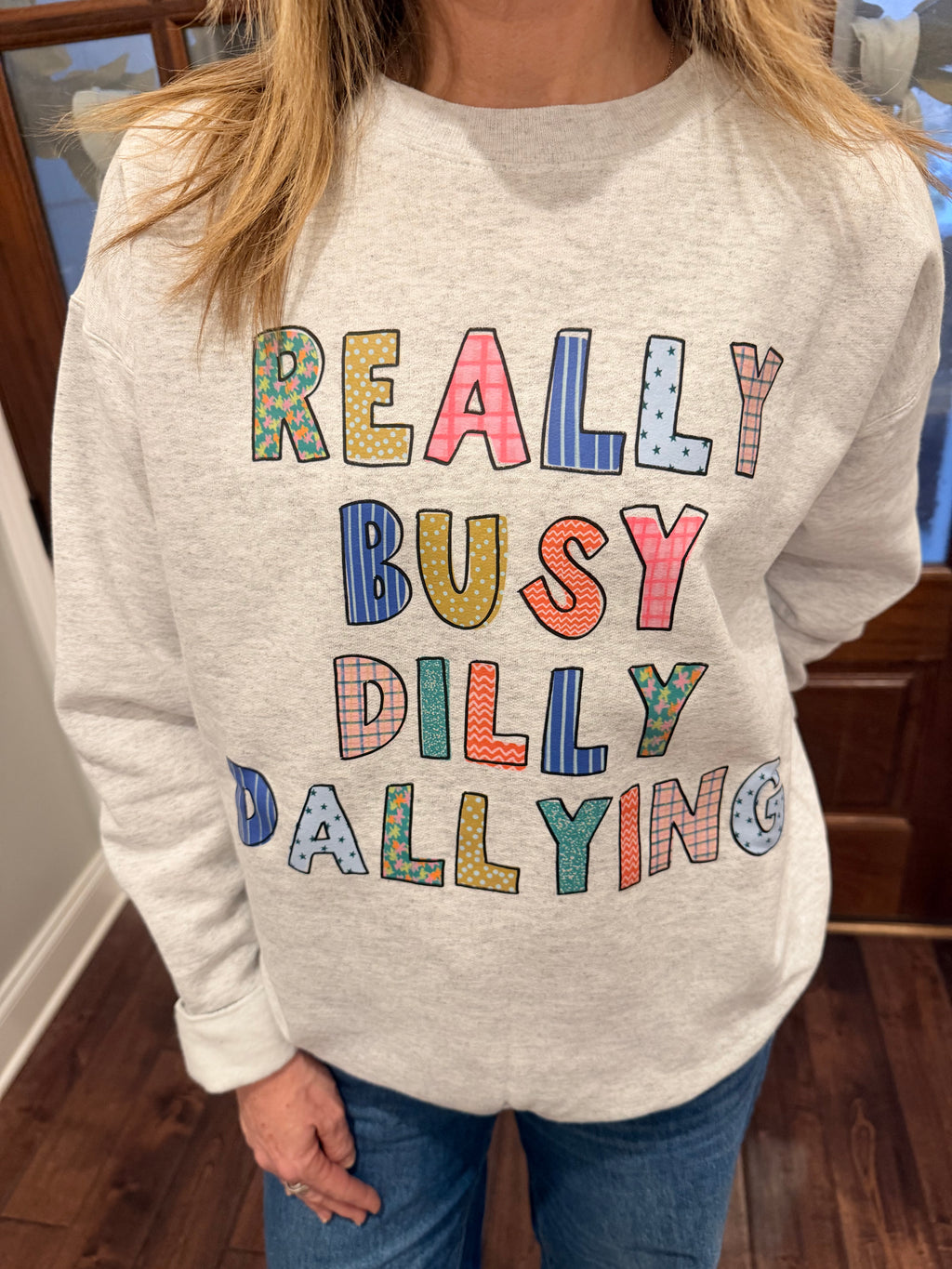 Person wearing a white sweatshirt with colorful text design indoors.