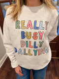 Person wearing a white sweatshirt with colorful text design indoors.