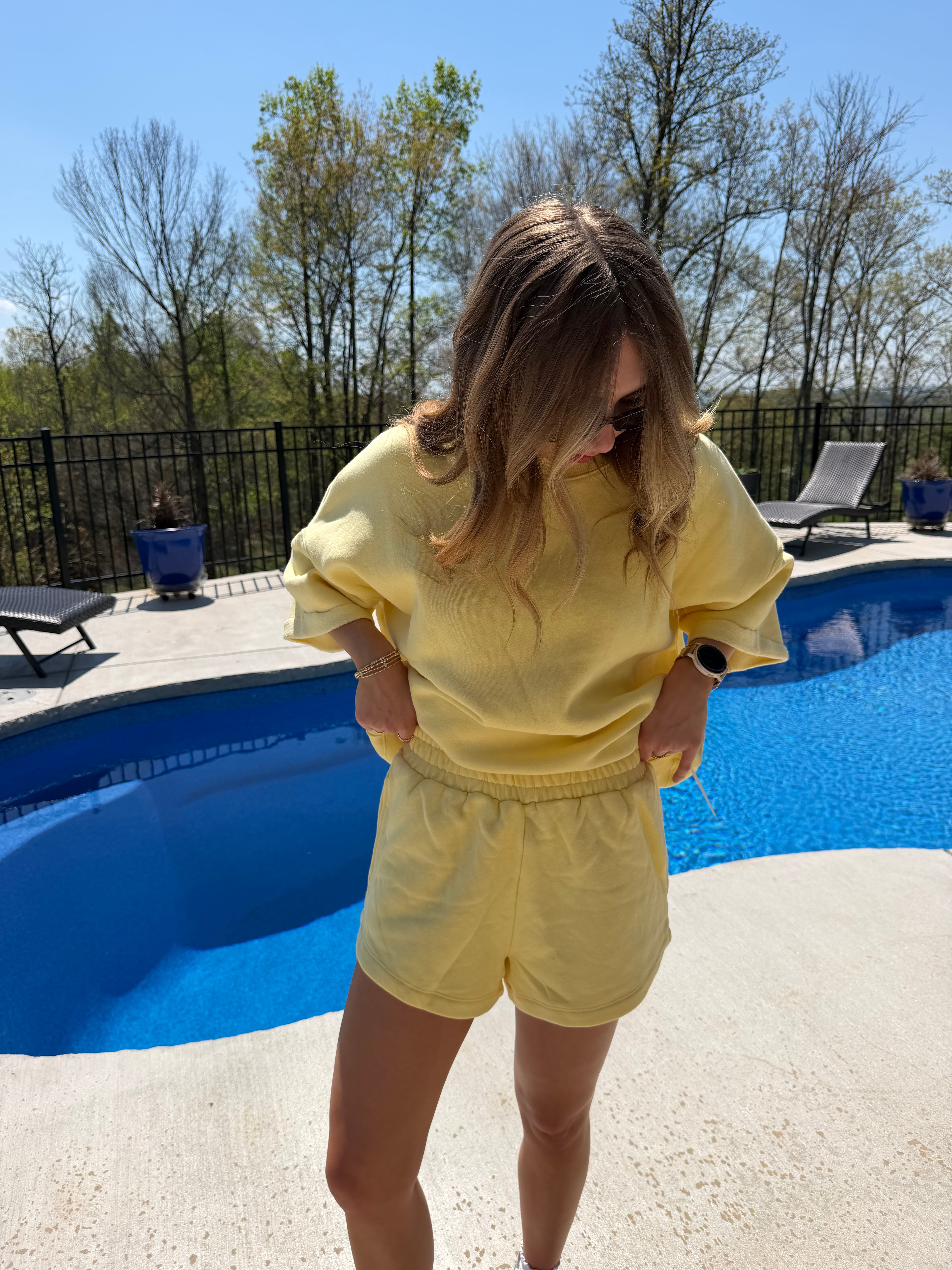 Person wearing a yellow outfit standing by a pool on a clear day.