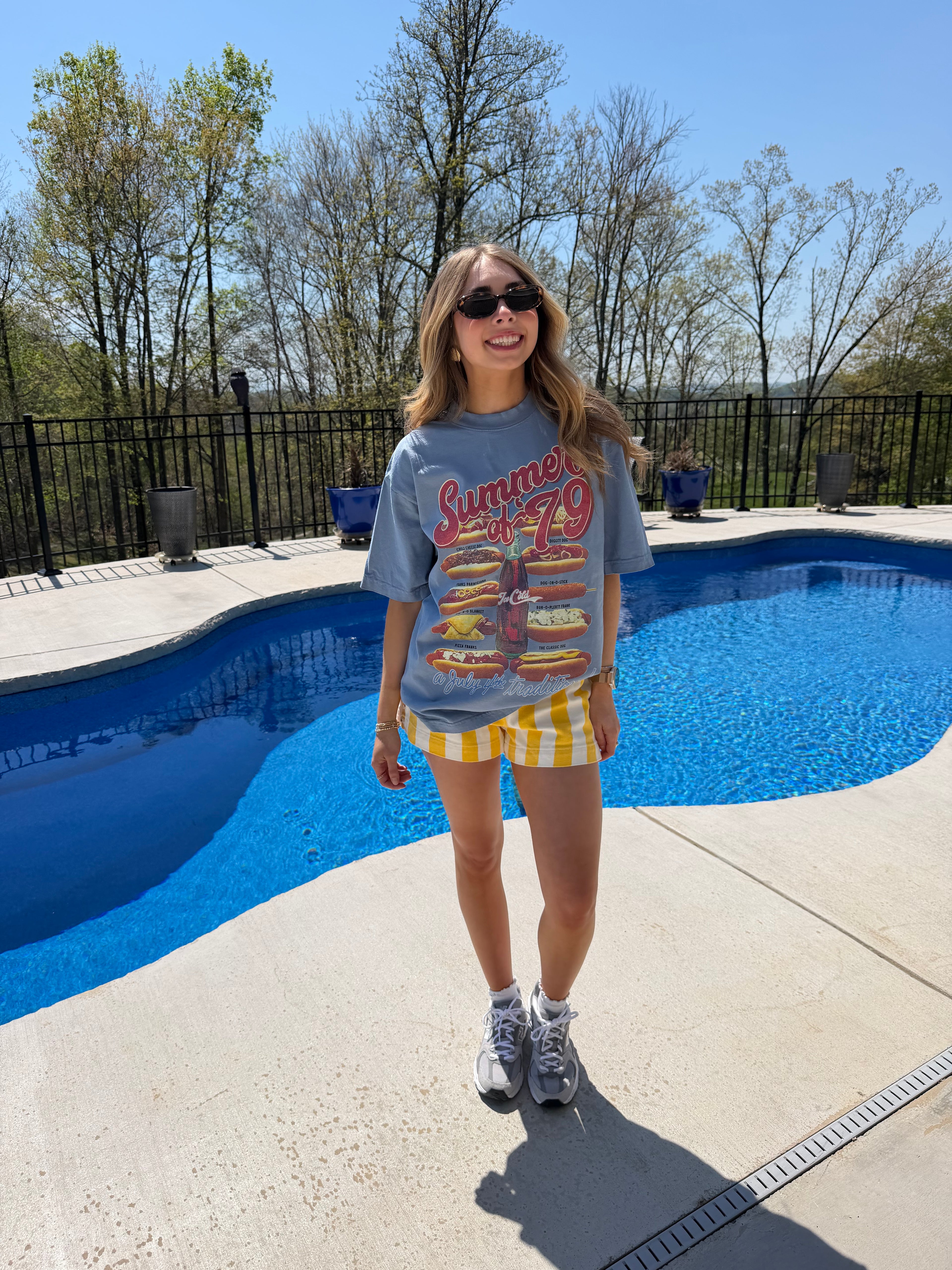 Person standing by a pool wearing a colorful shirt and shorts