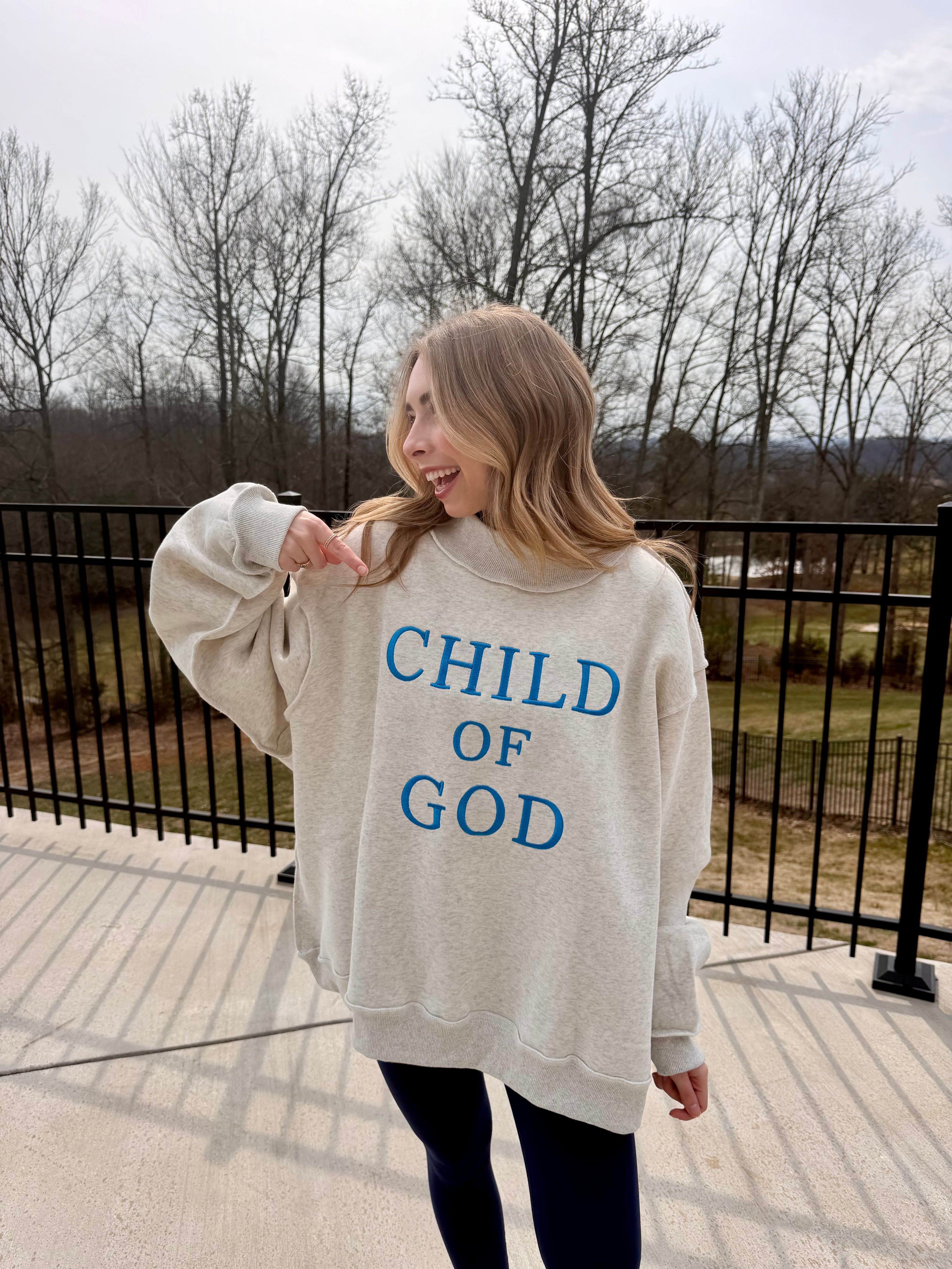 Person wearing a 'Child of God' sweatshirt outdoors on a cloudy day.