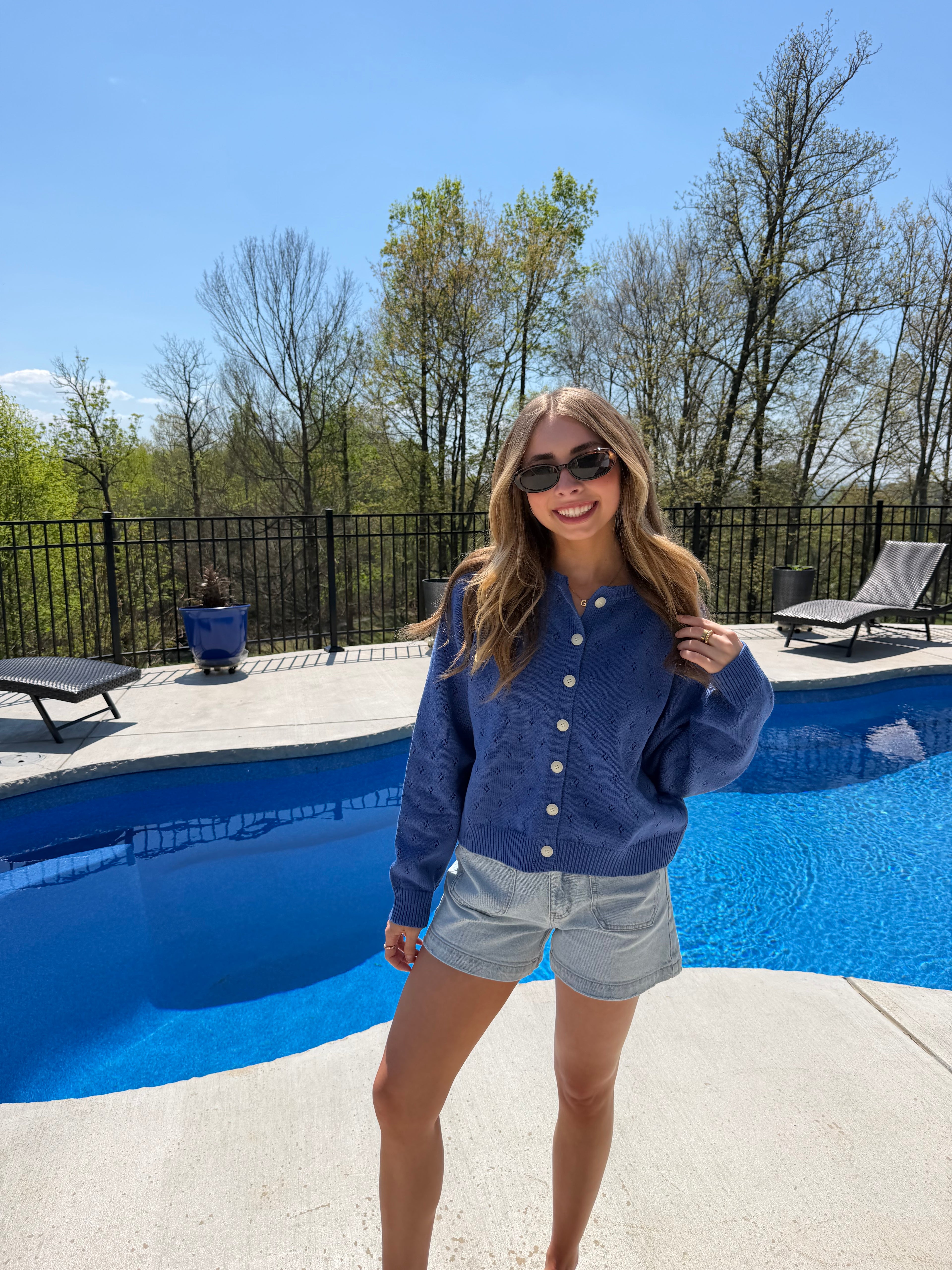 Woman standing by a blue pool cover on a sunny day