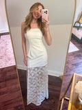 Woman taking a mirror selfie wearing a white dress with lace detailing.