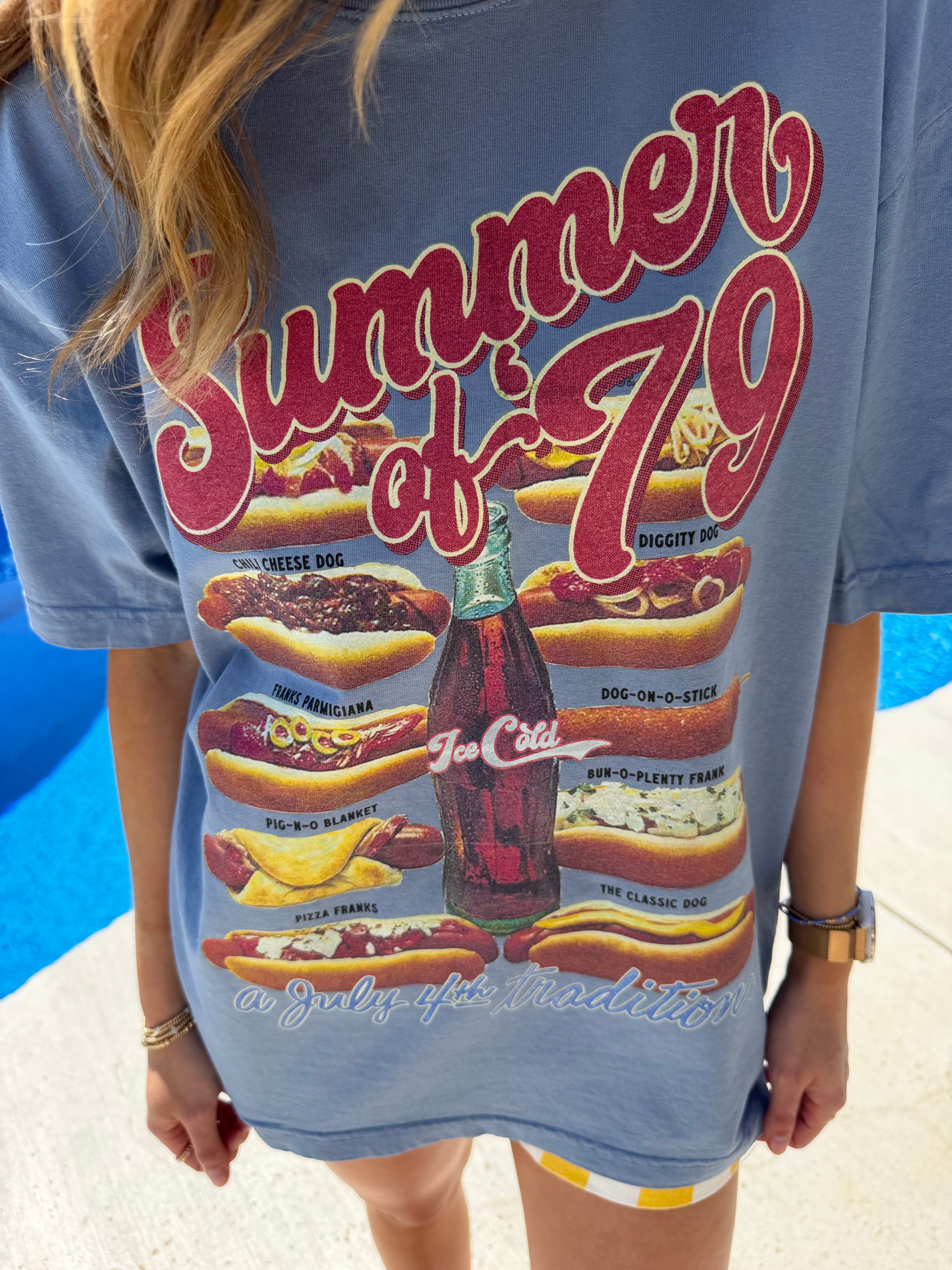 Person wearing a blue t-shirt with hot dog graphic and Coca-Cola bottle design.