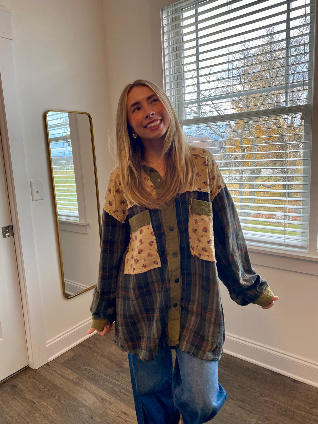 Woman standing in a room with a window and mirror in the background