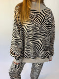 A person wearing a black and white zebra print long-sleeve top and matching pants against a plain white background.