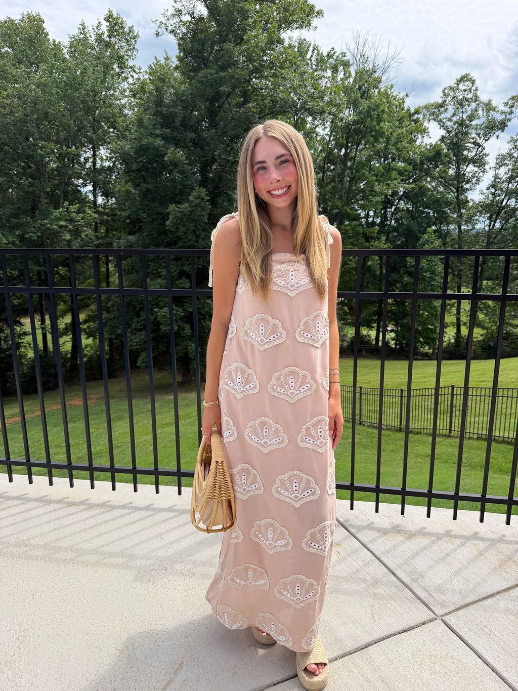 Woman in a long dress with a pattern standing outdoors on a sunny day.