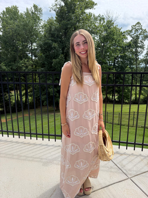 Woman in a patterned dress standing outdoors with trees in the background
