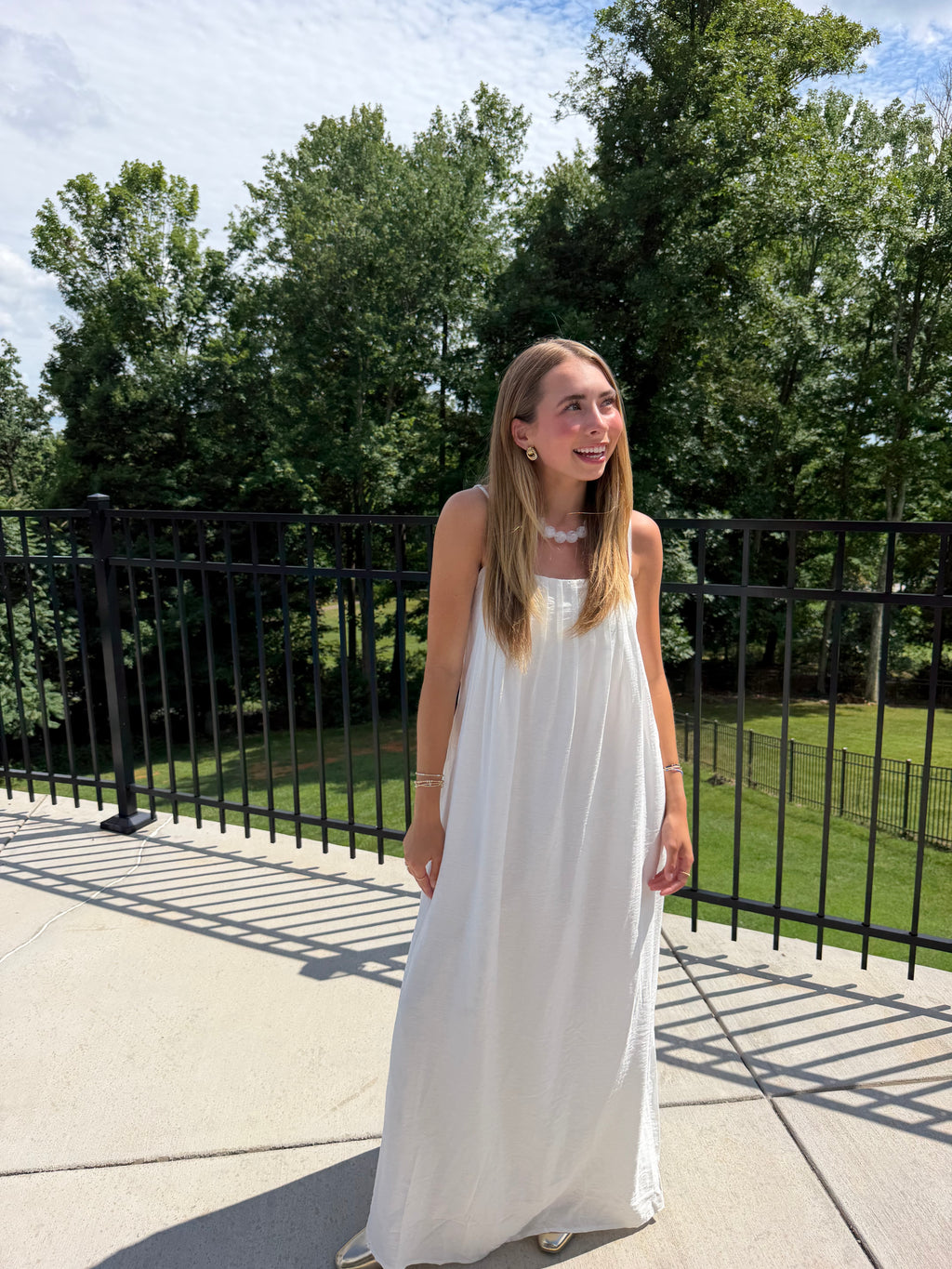Woman in a white dress standing outdoors with trees in the background