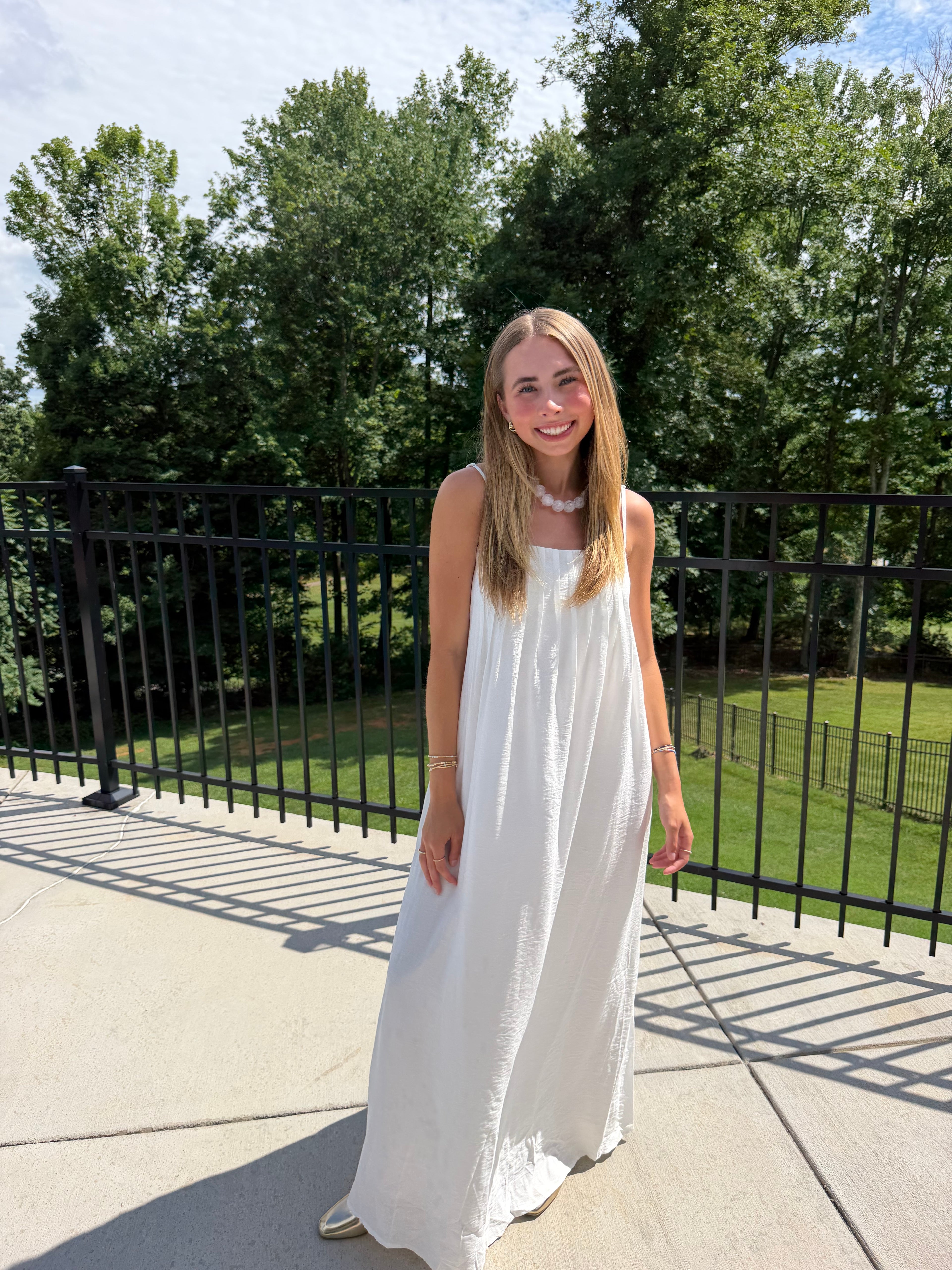 Woman in a white dress standing outdoors with trees in the background