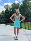 Woman in a blue striped dress standing on a patio with trees in the background