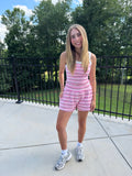 Young girl in a pink striped outfit standing outdoors with trees in the background