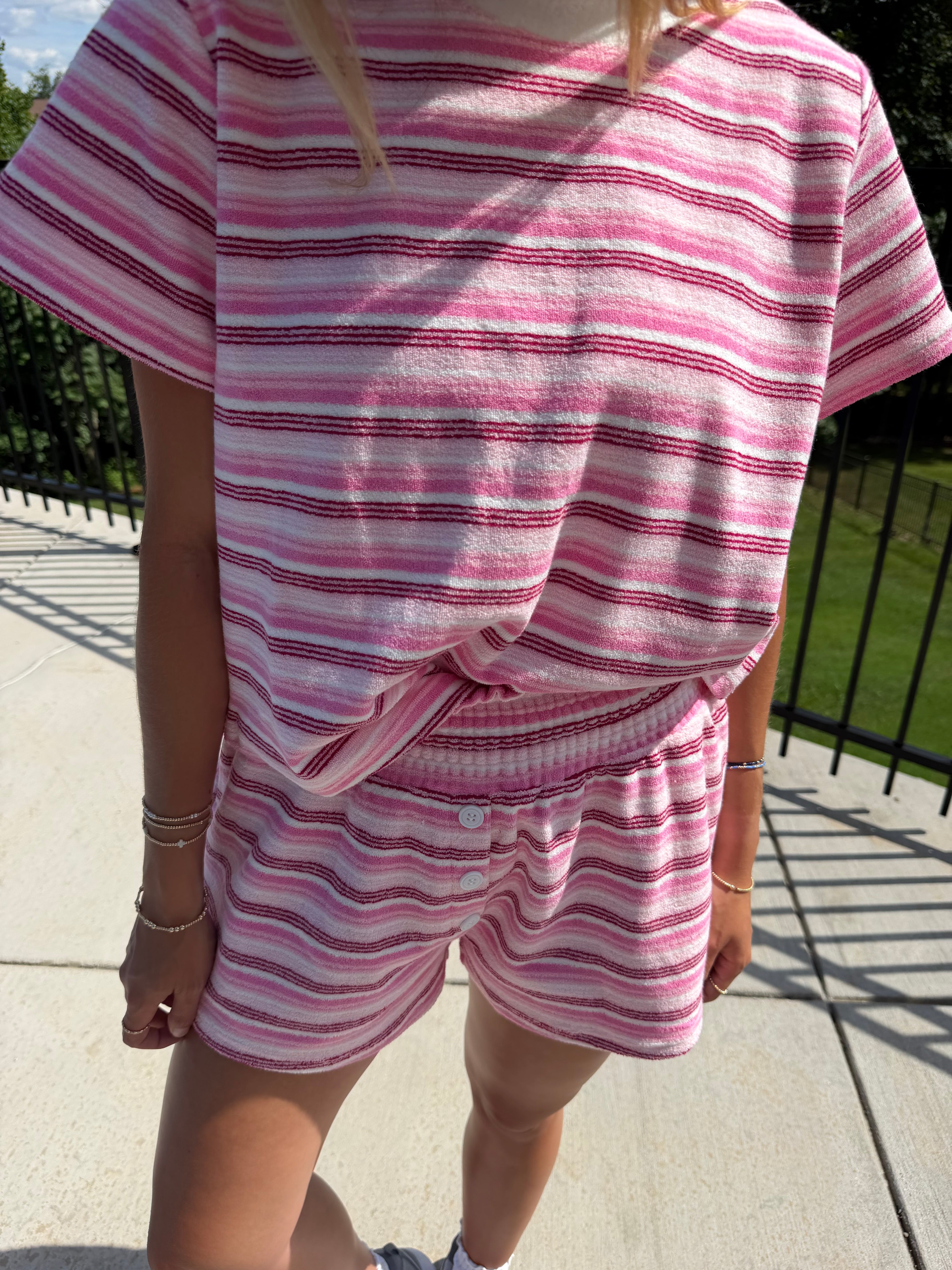 Person wearing a pink and white striped outfit on a sidewalk.
