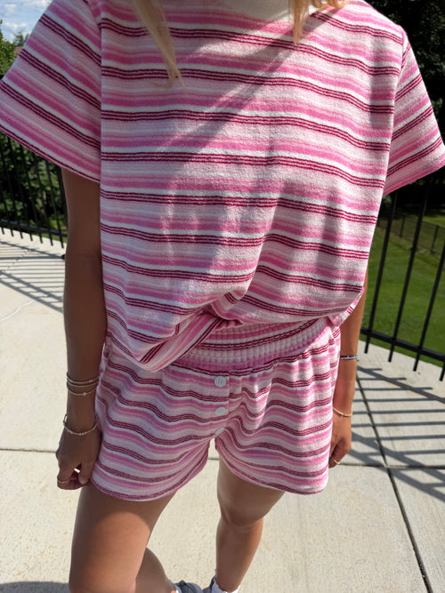Person wearing a pink and white striped outfit on a sidewalk.