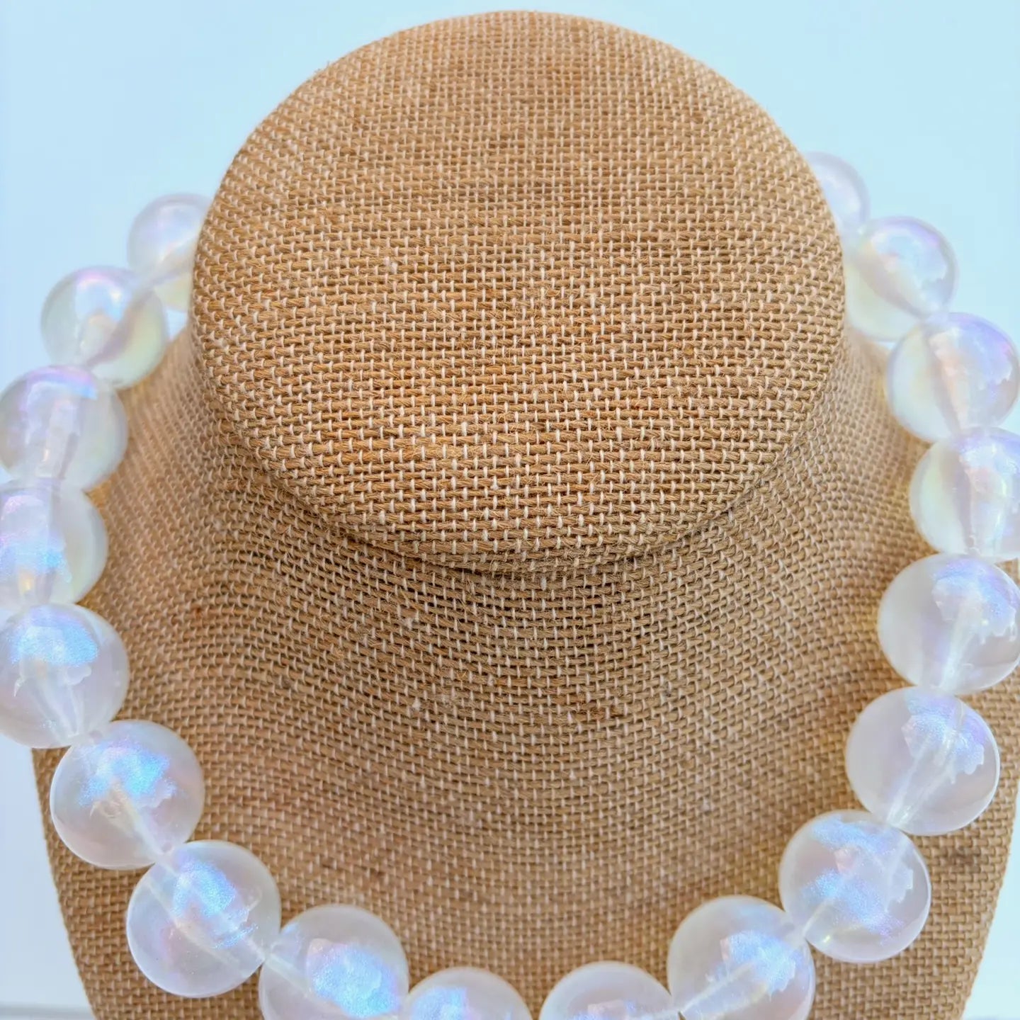 pearl necklace on a mannequin head against a light blue background