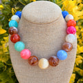 Colorful beaded necklace on a mannequin bust with a blurred floral background