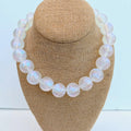 Pearl necklace on a brown jewelry display bust with a light blue background
