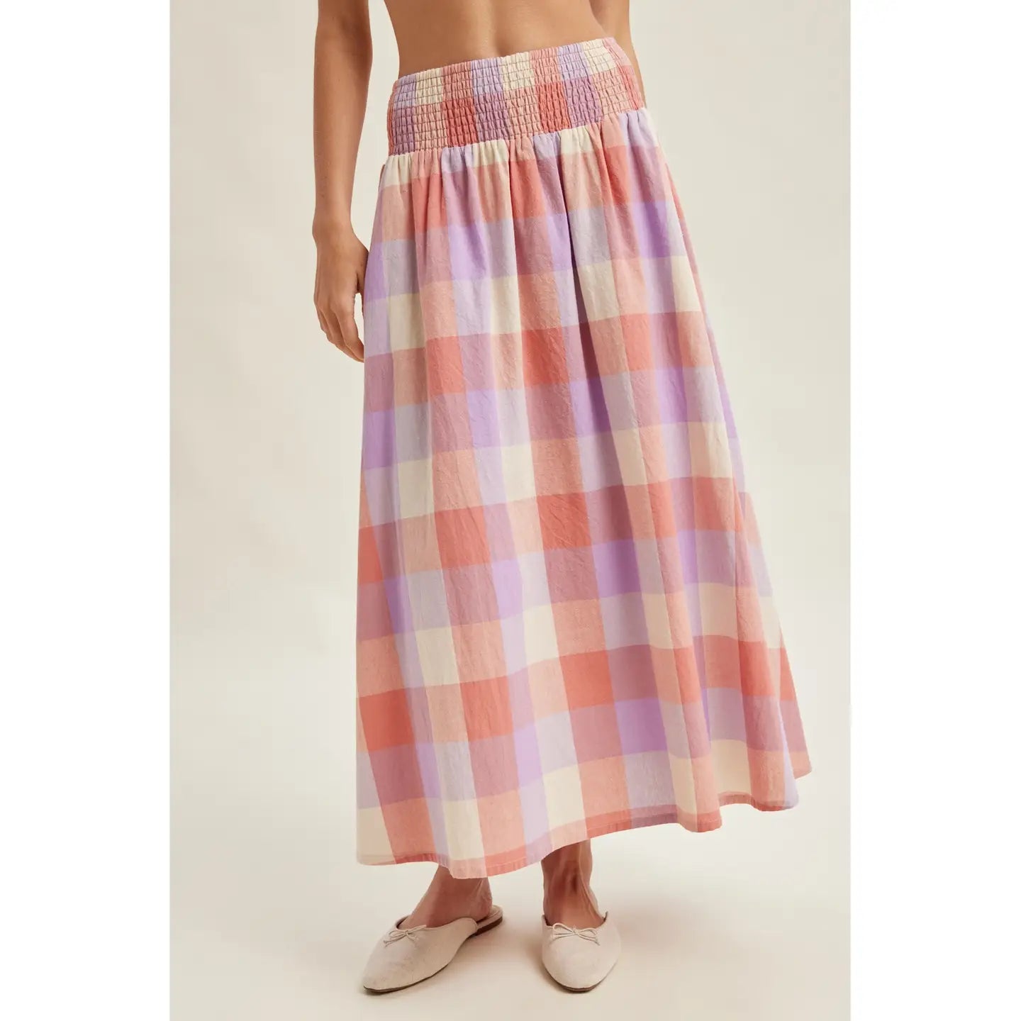 Person wearing a plaid skirt with a neutral background