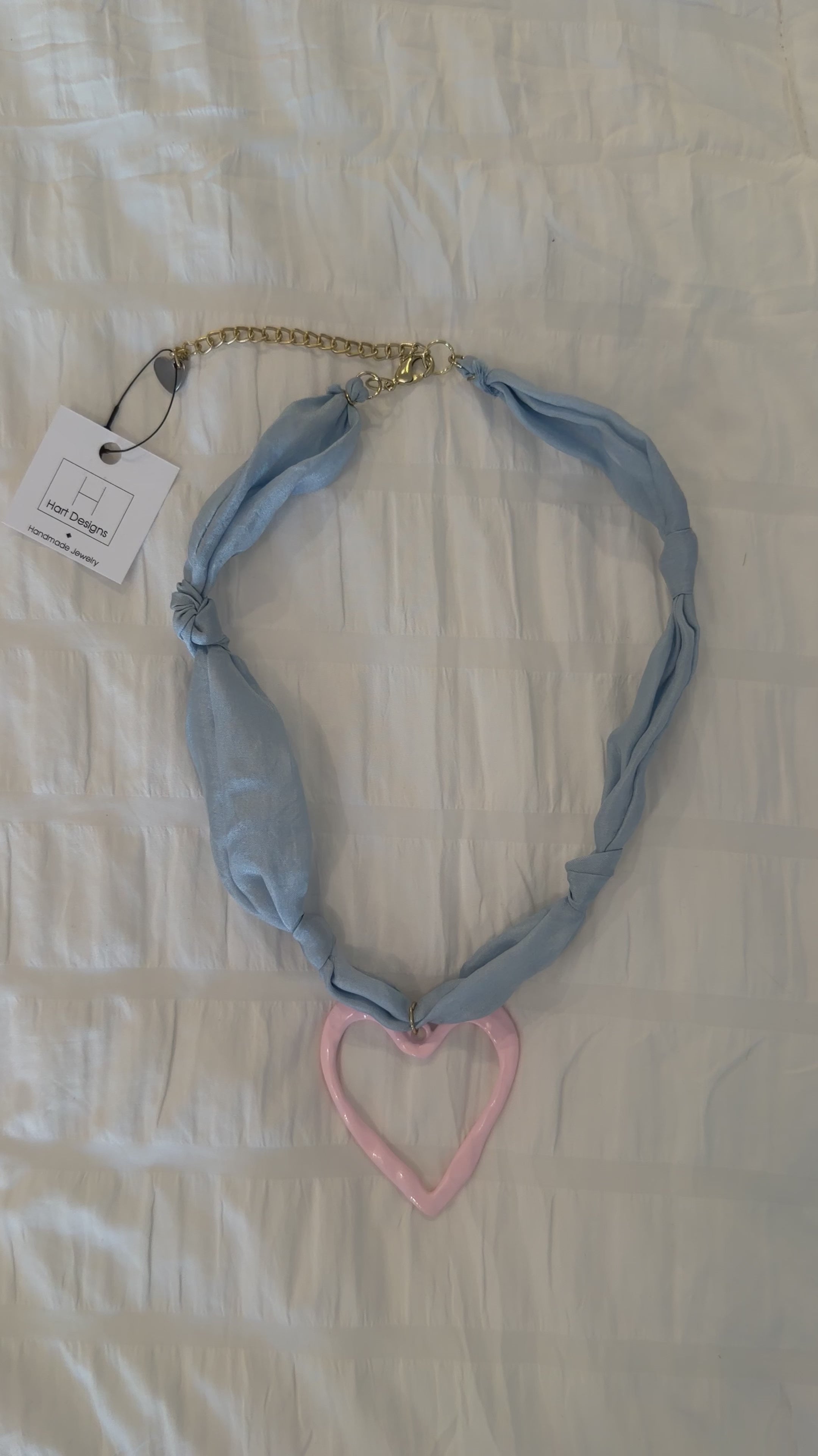 Necklace with a blue chain and pink heart on a light background